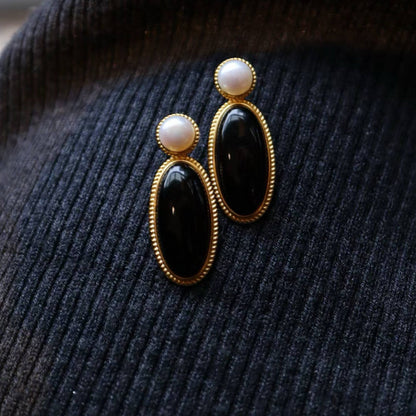 Elegant and unique drop earrings with gold vermeil textured frame, freshwater natural pearl and eclipse shaped natural black onyx gemstone.